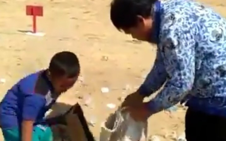 Seorang pria di bantu seorang anak kecil peduli bersihkan sampah usai upacara HUT RI