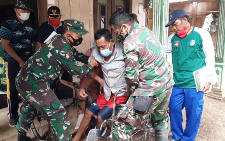 Satgas TMMD membantu Pak Slamet duduk di kursi roda. Rabu, 22/10/2020
