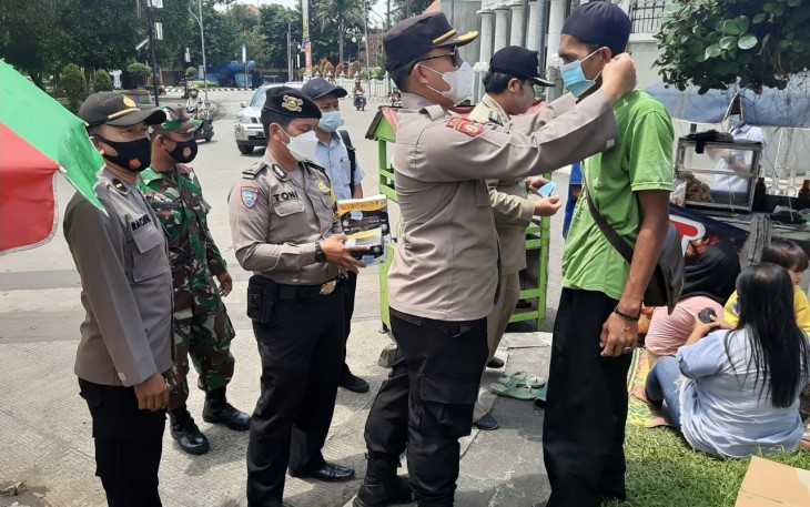 Kapolsek Pekalongan Utara Kompol Bakti Kautsar Ali,S.I.K,S.Sos memakaikan masker kepada masyarakat yang tidak taat prokes