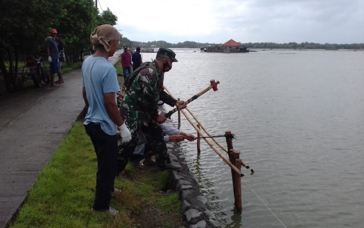 Koramil 0411/Teluk jambe Kodim 0604/KRW yang dipimpin oleh Kapten Inf Sukarya memonitoring dan membantu pelaksanaan pengerjaan turap jalan desa