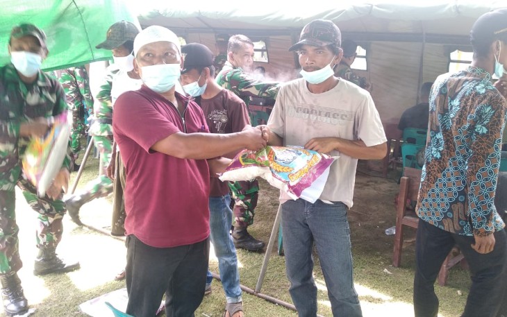 Kades Teluk Rumbia Kamaluddin (kiri) memberikan beras kepad warga usai menjalani vaksinasi yang dilaksanakan didesa setempat