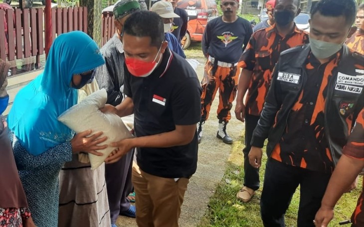 Anggota Komisi VIII DPR RI Paryono didampingi Ketua MPC Pemuda Pancasila Disa Agen Alifven sedang  menyerahkan bantuan sembako kepada warga kurang mampu di Desa Ngargoyoso, Kecamatan Ngargoyoso, Kabupaten Karanganyar, Jawa Tengah, pada Sabtu (18/12/2021)