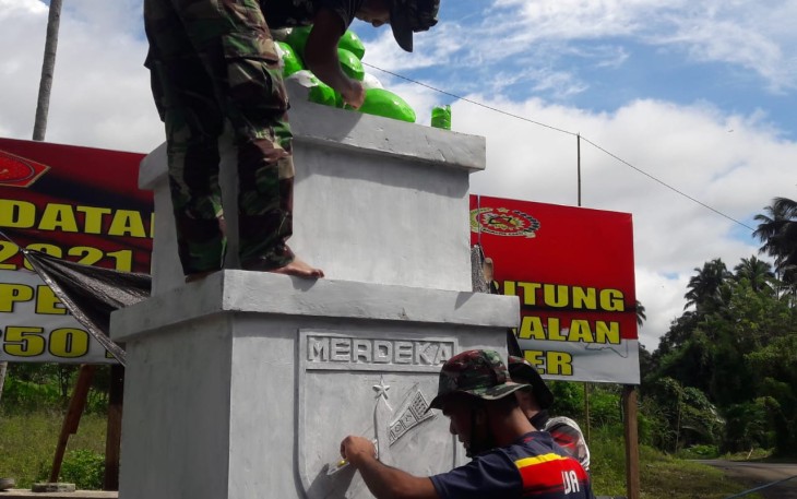 Personil satgas TMMD saat melakukan pengecetan tugu prasasti