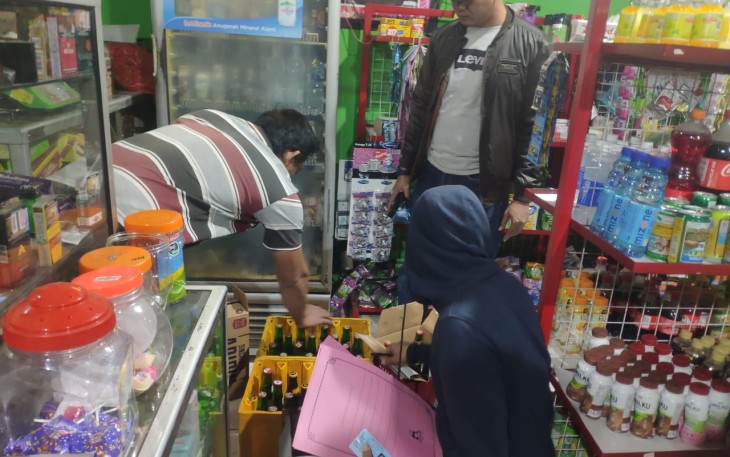 Anggota Sat Reskrim Polres Karanganyar tengah mengamankan puluhan botol miras dari toko kelontong milik S, di wilayah Pulosari, Kebakkramat, Kabupaten Karanganyar, pada Senin (29/8/2022) dini hari. (Foto : Istimewa).