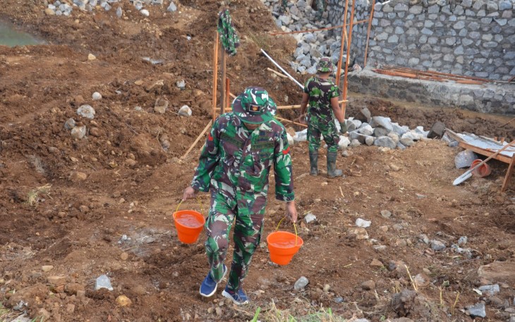 "Anggota Satgas TMMD sedang mengusung air dengan peralatan berupa ember"