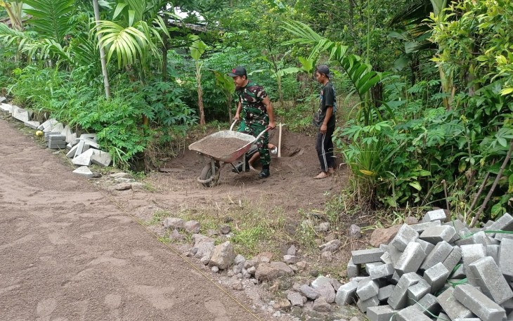 Babinsa Koramil 08/Jogorogo Kodim 0805/Ngawi Koptu Tria Purwanto bersama dengan warga binaan melaksanakan gotong-royong pemasangan paving jalan di Desa Ngrayudan Kecamatan Jogorogo, Senin (30/12/2024)