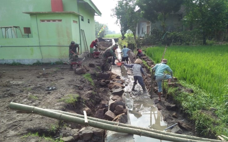 Babinsa Desa Garon, Koramil 03/Balerejo Kodim 0803/Madiun, Serda Akbar ikut serta dalam membantu pembangunan saluran irigasi bersama warga masyarakat sebagai bentuk kepedulian Babinsa dalam mewujudkan peningkatan pembangunan desa, Rabu (27/12/2023)
