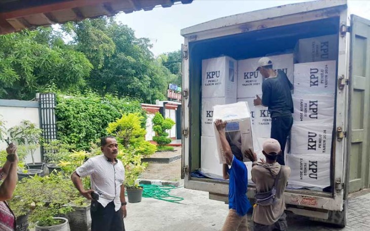 Pekerja sedang mengangkat kotak logistik Pemilu 2024 yang tiba di kantor kecamatan Cepu dengan pengawalan ketat dari aparat TNI-Polri.