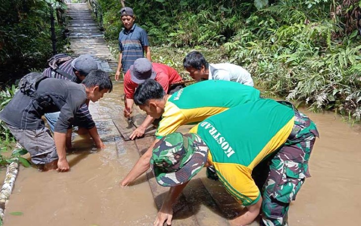 Satgas Pamtas Yonarmed 10 Kostrad saat Bantu Warga Perbatasan Perbaiki Jembatan