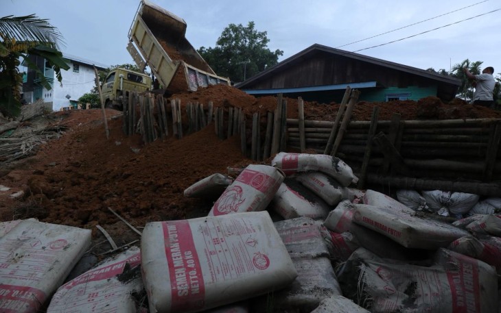 Truk milik Dinas Pekerjaan Umum menumpahkan material tanah untuk menutup tanggul yang jebol di wilayah Tanjung Pura, Kabupaten Langkat, Sumatra Utara, Jumat (12/12).