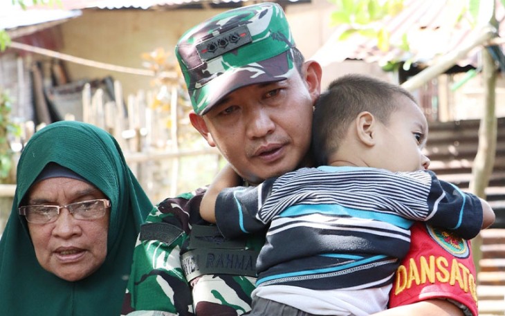 Menunjukan kasih sayang, Dandim 0407/Kota Bengkulu Kolonel Inf Widi Rahman menggendong buah hati pasutri penerima rehab RTLH.