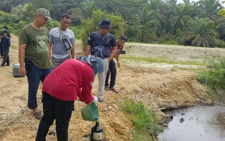 Pihak Polres dan DLH Aceh Singkil saat melakukan penyelidikan dan mengambil sampel air sungai yang tercemar.