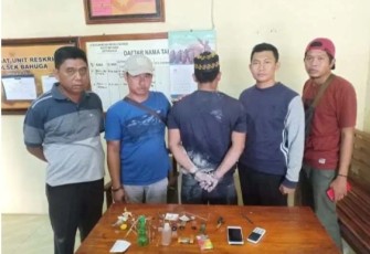 Tersangka (Tengah Diborgol) saat diamankan berikut barang bukti