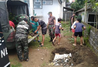 Personil satgas TMMD kodim Bitung di bantu anak-anak sekitar Lokasi saat Pindahkan Bibit Pohon