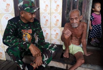 Serma Agus Prayitno, anggota Satgas TMMD Reguler ke 115 saat berkunjung ke rumah Bapak Badrun (90). 