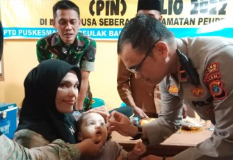 Polisi saat berikan vaksin polio kepada balita.