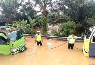 Petugas saat berupaya mengevakuasi truk terjebak banjir