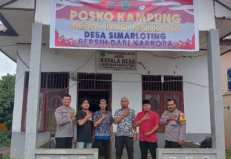 Bhabinkamtibmas Polsek Padang Bolak, Aipda Nyamano Manik, memasang spanduk Posko Kampung Bebas dari Narkoba, Selasa (24/10/2023) siang.