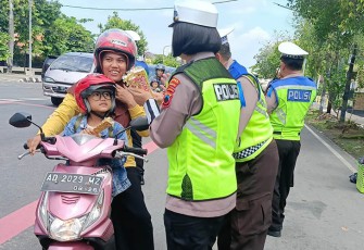 Anggota Satlantas Polres Karanganyar sedang memberikan cokelat dan bunga kepada pengendara sepeda motor, Senin (4/3/2024).