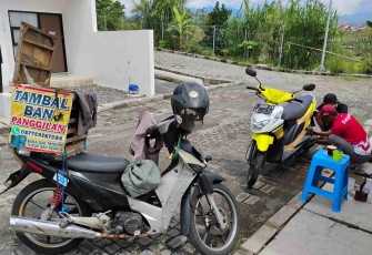 Sugianto, saat tengah melayani pelanggan dengan menambal ban sepeda motor yang bocor. Selasa (11/11)