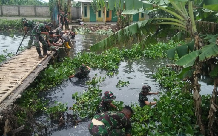 Anggota Koramil saat membersihkan sampah dan eceng gondok di Kali Babelan