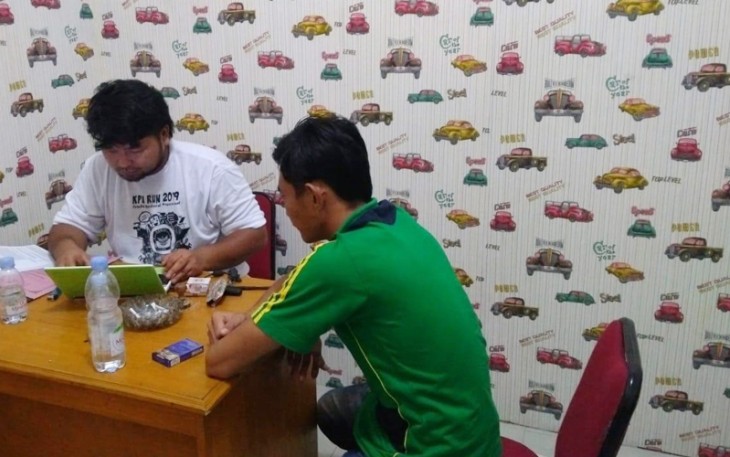 Tersangka mengenakan kaos hijau saat diperiksa penyidik