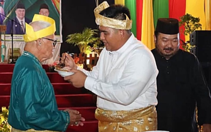 Bupati Bintan Roby Kurniawan SPWK saat memyuapkan nasi tumpeng ke tetua Kabupaten Bintan, Sabtu (03/12/2022).