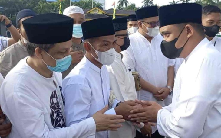 Suwarno (masker hitam) saat bersalam-salaman usai shalat Ied di lapangan Merdeka Medan. Senin (02/05/2022)