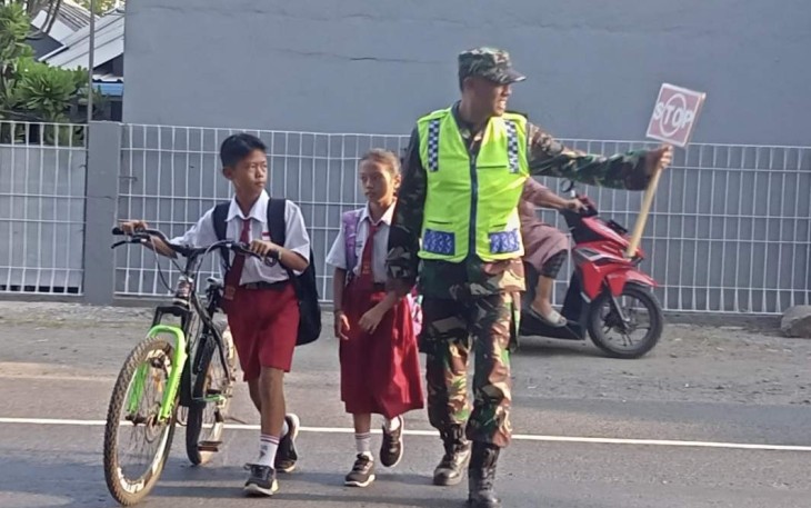 Sertu Sodikin bantu menyeberangkan anak sekolah di wilayah binaan, Selasa (10/10) 