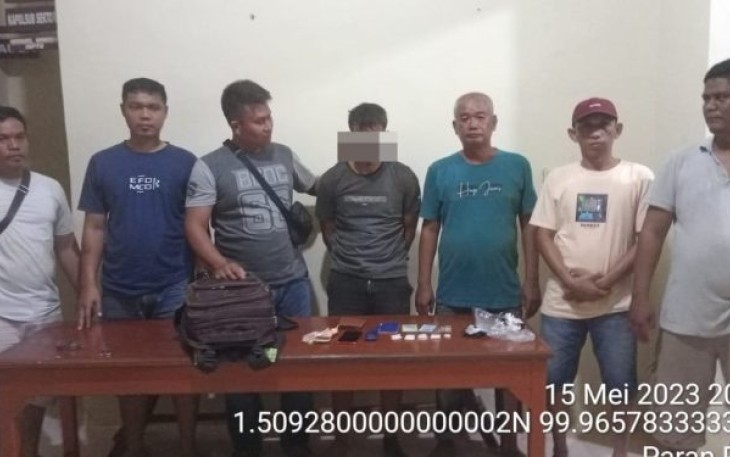 Tersangka Em saat diamankan personel Polsubsektor Simangambat