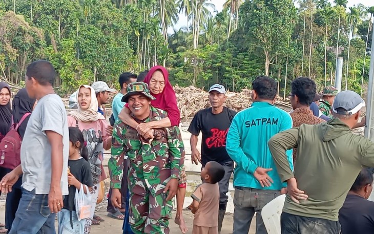 Babinsa Kodim Bireuen Gendong Lansia Lintasi Material Banjir