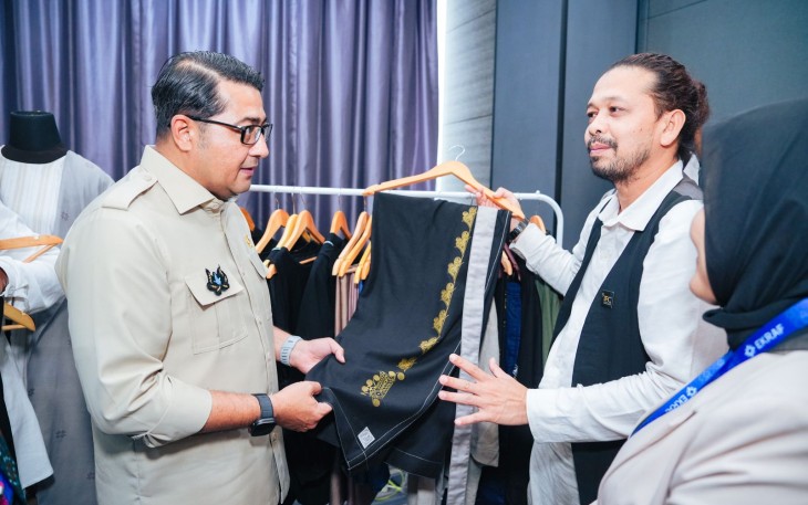 Menteri Ekonomi Kreatif, Teuku Riefky Harsya, meninjau produk fesyen pada acara Bootcamp II Akselerasi Fesyen Muslim Indonesia, Aceh, Selasa (25/11/2025).