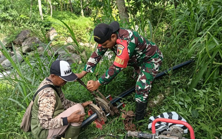 Babinsa Jogorogo saat Bantu Pemasangan Pipa Saluran Air Bersih untuk  warga Dusun Bungkus, Desa Ngrayudan, Kecamatan Jogorogo Kabupaten Ngawi, Kamis (4/12/2025).