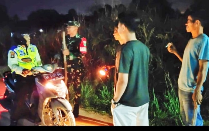 Serka Agus Supraptono, Bintara Pembina Desa (Babinsa) Komando Rayon Militer dan (Koramil) 03/Binut, saat melaksanakan monitoring kegiatan dalam menjaga di lingkungan bersama Linmas, Ketua RT serta masyarakat, Minggu (14/09/2025) malam.