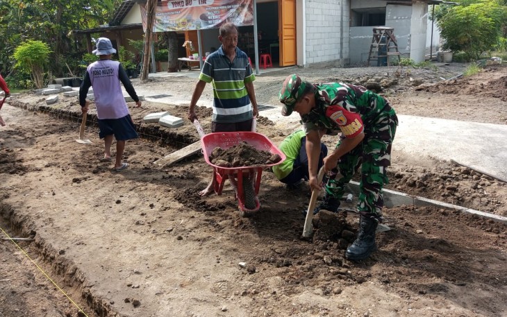 Babinsa Desa Pulerejo Bersama Warga Sukseskan Kerja Bakti Pemasangan Paving