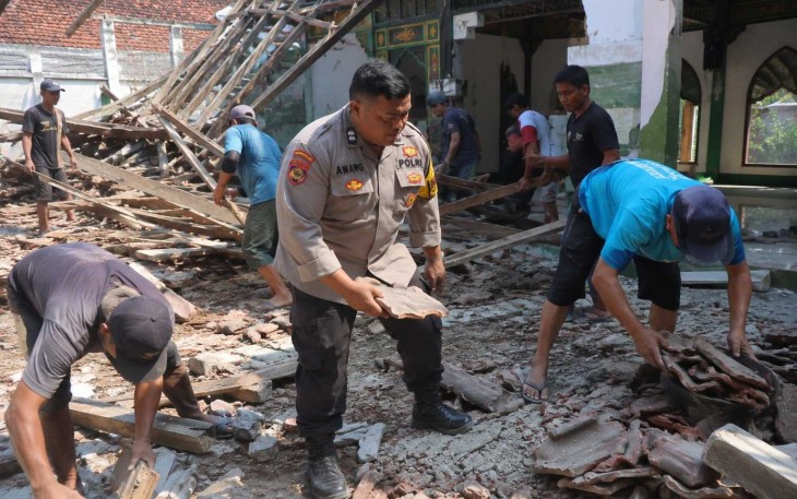 Aiptu Awang membersihkan material Masjid Al Islah yang atapnya ambruk bersama warga, Selasa (18/8)
