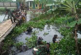 Anggota Koramil saat membersihkan sampah dan eceng gondok di Kali Babelan