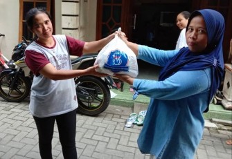 Anggota komunitas Solo Brompton Owners (SOBO) sedang membagikan paket sembako kepada warga.