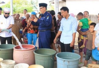 Wali Kota Bengkulu Helmi Hasan Mengenakan Peci Putih Sedang Menuang Air Kedalam Ember 