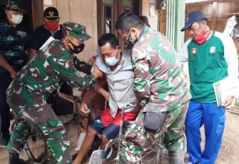 Satgas TMMD membantu Pak Slamet duduk di kursi roda. Rabu, 22/10/2020