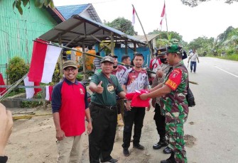 Danramil 04/Sangasanga Kapten Inf Priyanto saat bagikan bendera merah putih kepada warga 