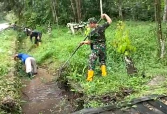 Serka Irfan saat membersihkan saluran air