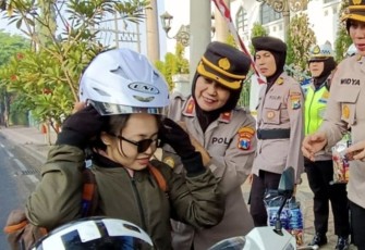 Polwan Polda Jatim saat memberikan helm gratis jelang HUT Polwan ke 75, Kamis (31/8)