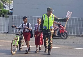 Sertu Sodikin bantu menyeberangkan anak sekolah di wilayah binaan, Selasa (10/10) 