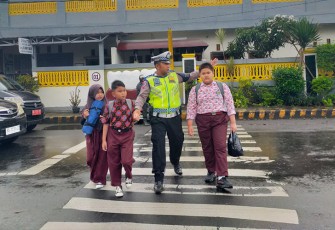 Polisi saat membantu anak-anak menyebrang jalan.