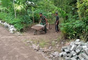 Babinsa Koramil 08/Jogorogo Kodim 0805/Ngawi Koptu Tria Purwanto bersama dengan warga binaan melaksanakan gotong-royong pemasangan paving jalan di Desa Ngrayudan Kecamatan Jogorogo, Senin (30/12/2024)