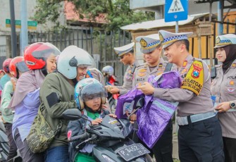 Kasat lantas Polres Jember AKP Bernardus Bagas saat membagikan jas hujan, Senin (10/2)
