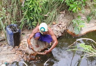 Salah satu warga Kedinding bernama Yanto sedang mengambil tumpahan minyak mentah yang mengalir ke sungai dengan cara manual atau istilahnya di pluntur.