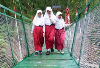 Sukacita siswa melintas di jembatan gantung perintis dusun Karang