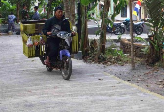 Pak Ramli penjual sayuran melewati jalan rabat beton